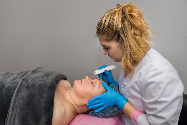 Une femme reçoit un gommage facial par cavitation ultrasonique Cosmétologie et soins de la peau Soins du visage Nettoyage du visage