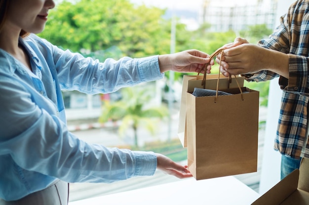 Une femme reçoit des sacs à provisions d'un livreur à domicile