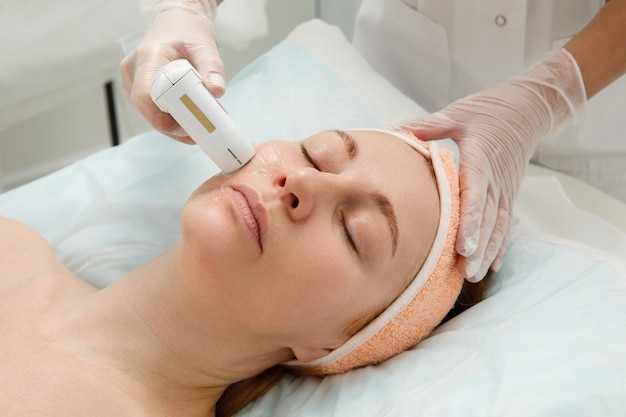 Une femme reçoit un traitement au laser du visage dans une clinique de cosmétologie un concept de rajeunissement de la peau est en cours de développement