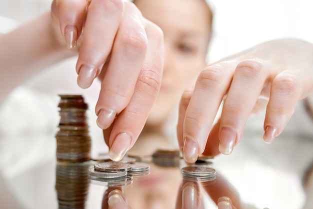 Une femme recueille une pile de pièces éparpillées sur une table miroir. photo de haute qualité