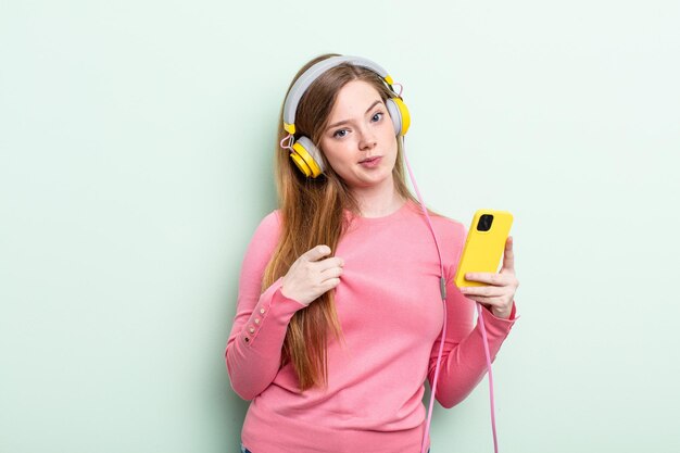 Femme Redhair à la recherche d'arrogance, de succès, de positif et de fierté. casque et concept de smartphone