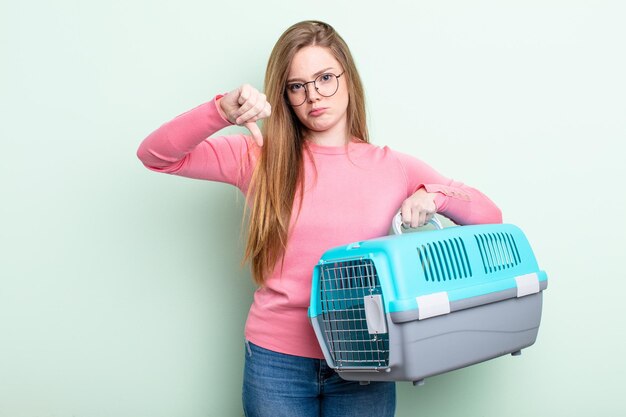 Femme Redhair se sentant croisée, montrant les pouces vers le bas. concept de transporteur pour animaux de compagnie de voyage