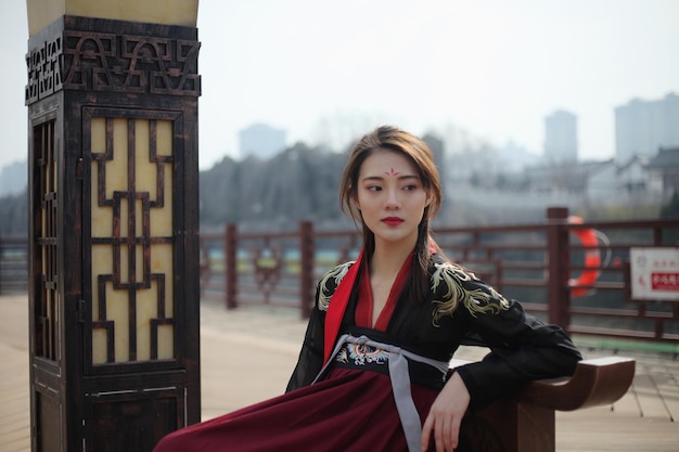 Une femme réfléchie portant des vêtements traditionnels alors qu'elle est assise sur un siège en ville