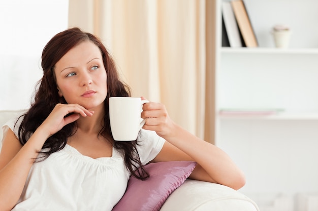 Femme réfléchie tenant une tasse