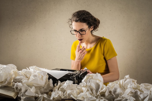 Photo femme réfléchissant sur sa machine à écrire