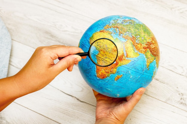 Photo une femme regardant l'afrique sur un globe à l'aide d'une loupe