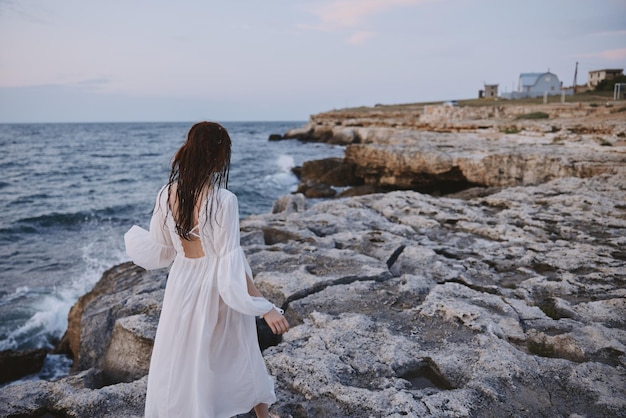 Une femme regardant au loin le paysage, les rochers, l'océan.