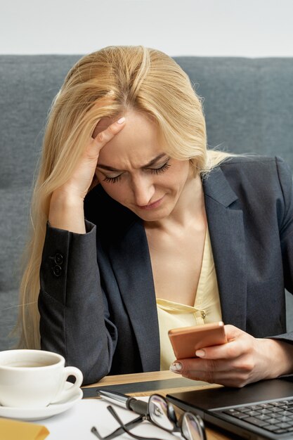 Femme regardant bouleversé lors de l'utilisation de smartphone.