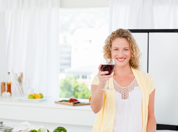 Femme regardant la caméra avec sa boisson de vin