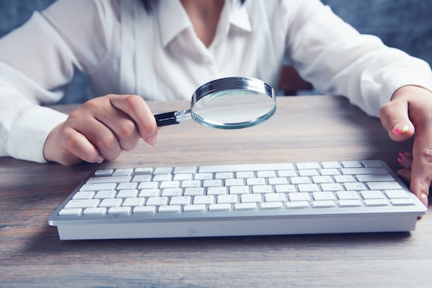 Femme regardant le clavier avec une loupe