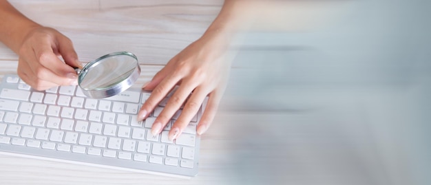 Femme regardant le clavier avec une loupe