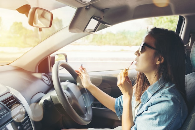 femme regardant dans le rétroviseur et maquillage en voiture