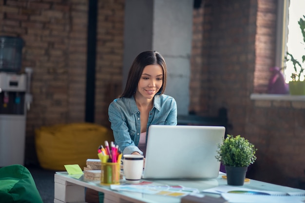 Femme regardant l'écran du portable tout en travaillant