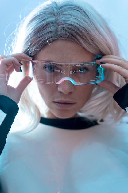 Femme regardant avec les lunettes futuristes illuminées fond bleu avenir et concept de réalité virtuelle