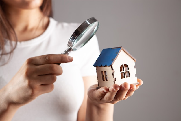 Femme regardant la maison à travers une loupe