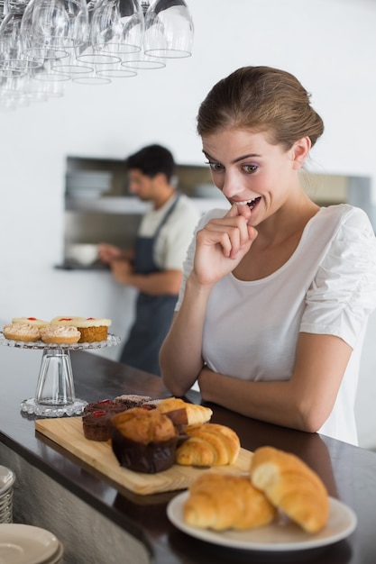 Femme regardant des mets sucrés au café