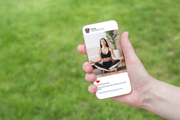 Femme regardant la photo d'un beau modèle faisant du yoga sur un téléphone portable