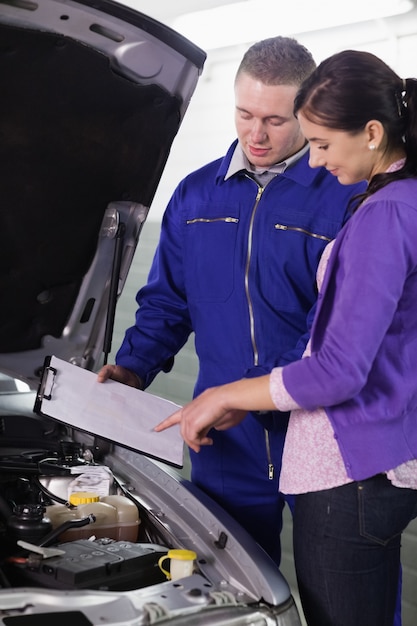 Femme regardant le presse-papiers à côté d&#39;une voiture