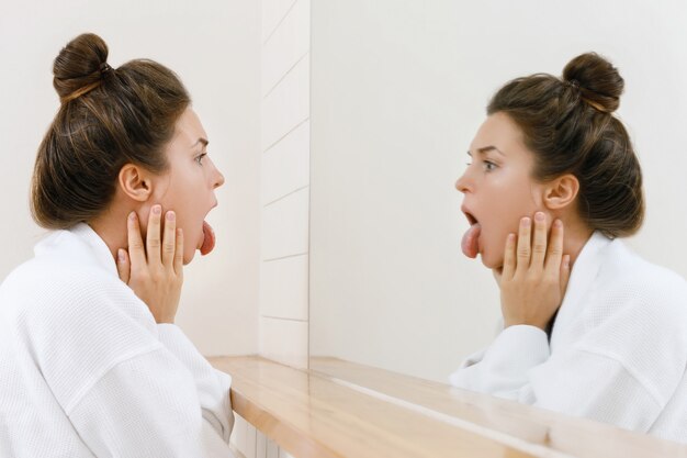 Femme regardant sa langue dans le miroir