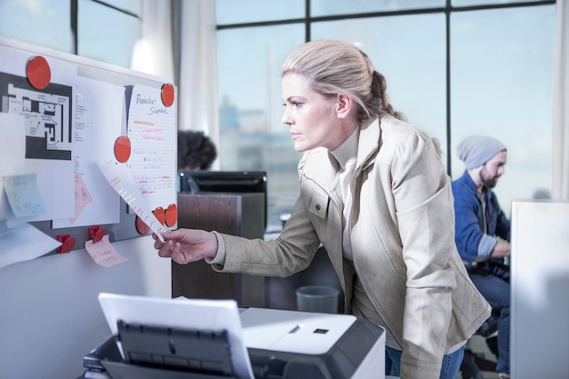 Femme regardant le tableau d'affichage au bureau