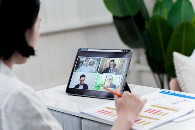 Femme regardant sur tablette pour conférence téléphonique avec rapport d'activité. travail de concept à domicile avec la technologie de communication internet en ligne.