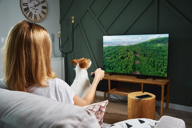 Femme regardant la télévision sur le canapé