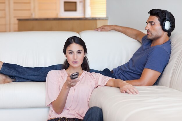 Femme regardant la télévision pendant que son petit ami écoute de la musique