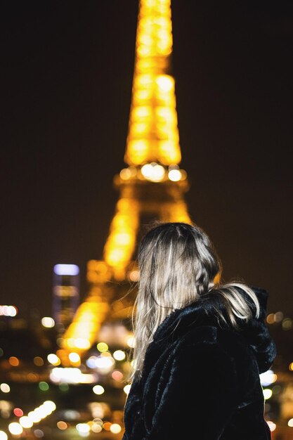 Photo une femme regardant la tour eiffel illuminée