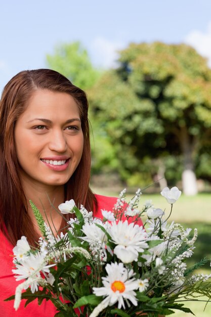 Photo femme regardant vers les fleurs de côté dans un parc