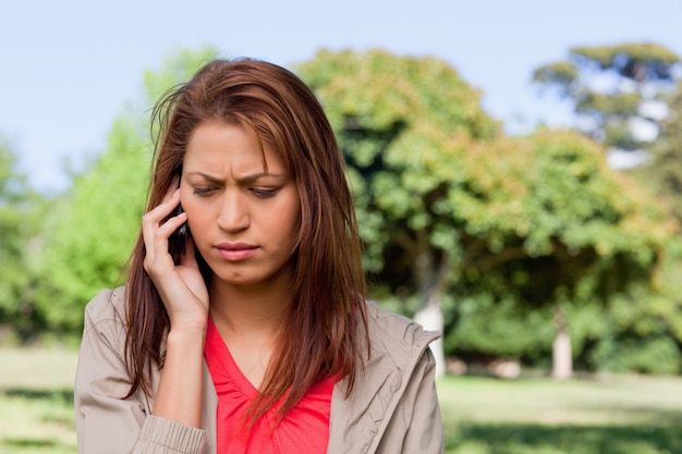 Femme regardant vers le sol tandis que sur le téléphone dans une zone de prairie lumineuse