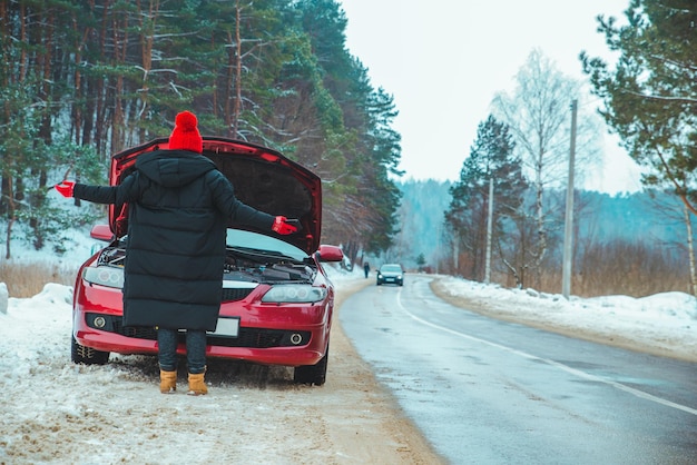 Femme regardant la voiture cassée au moteur à l'espace de copie côté route d'hiver