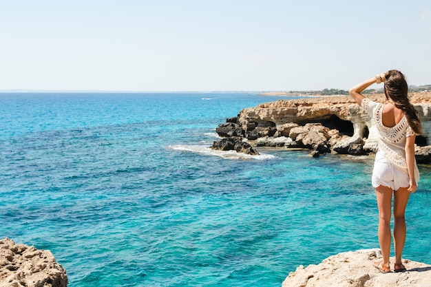 Femme regardant la vue imprenable depuis le célèbre point de vue du cap Greco alors qu'elle se tient au bord d'une falaise