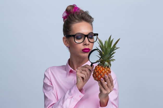 Femme regarde l'ananas à travers la loupe