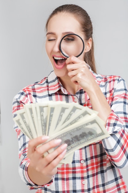 La femme regarde dans la loupe sur les billets d'un dollar