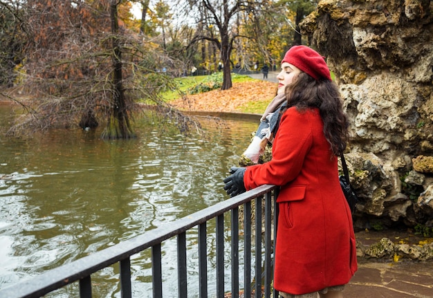 La femme regarde fixement un pont en parc automnal