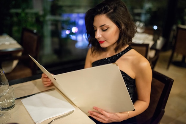 Une femme regarde un menu dans un restaurant.