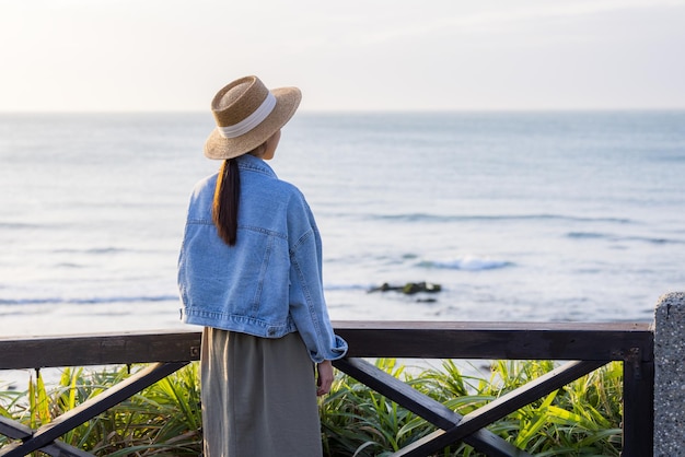 Femme regarde la mer au coucher du soleil