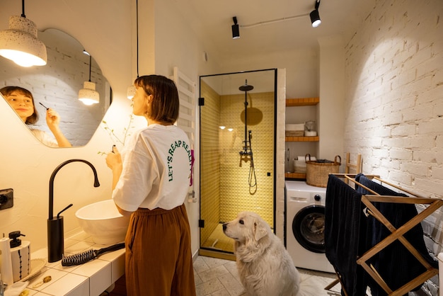 La femme regarde sur le miroir dans la salle de bains