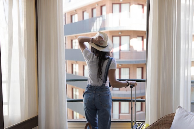 Une femme regarde par la fenêtre d'un hôtel