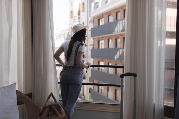 Une femme regarde par la fenêtre d'un hôtel