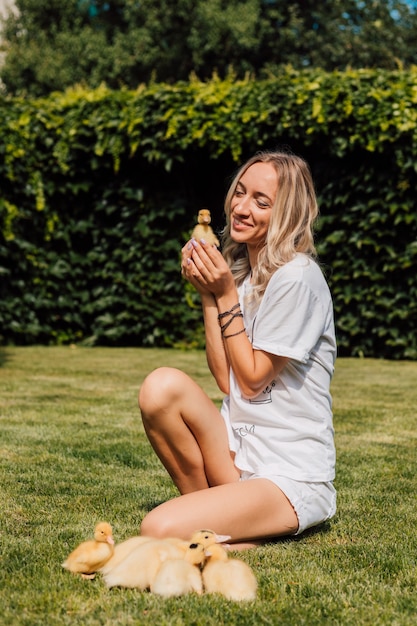 La femme regarde le petit caneton jaune et sourit