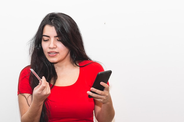 Une femme regarde son téléphone et tient un maquillage.