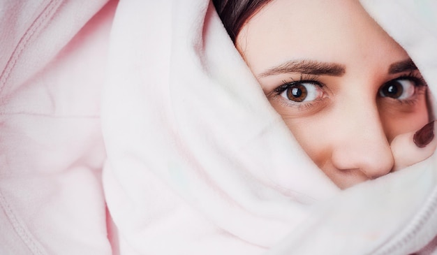 Une femme regarde sous la couverture Femme se cachant sous une couverture