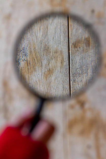 une femme regarde la texture d'une table avec une loupe