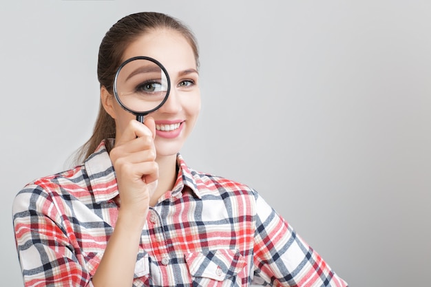 La femme regarde à travers une loupe