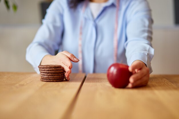 Femme rejetant la malbouffe ou les aliments malsains tels que les biscuits ou le dessert et choisissant des aliments sains