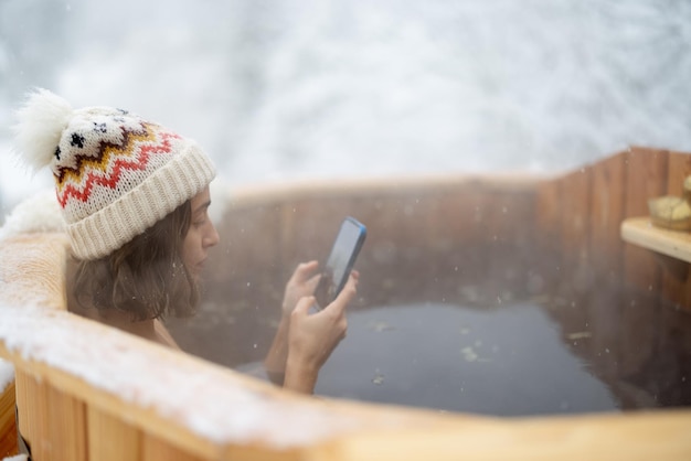 Photo femme relaxante dans un bain chaud dans les montagnes enneigées