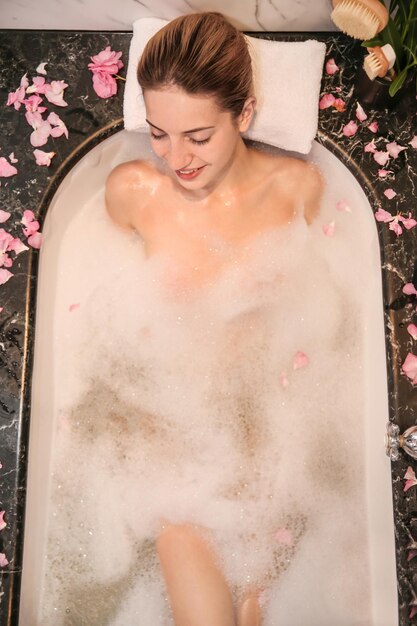 Femme relaxante dans un bain avec concept de traitement de spa en mousse