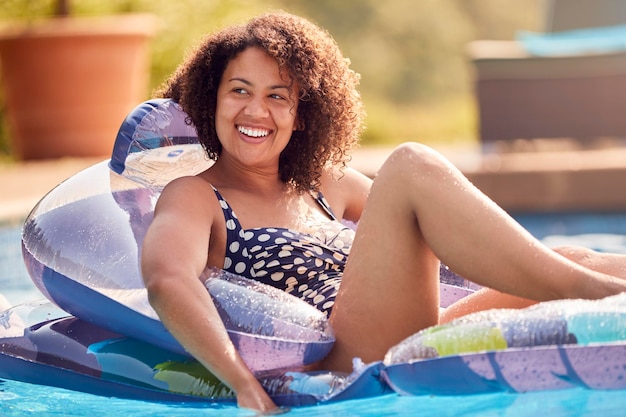 Femme relaxante flottant sur gonflable dans la piscine pendant les vacances d'été