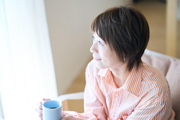 Femme relaxante près de la fenêtre